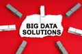 On a red background, there are clothespins and a piece of paper with the inscription - Big Data Solutions