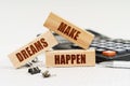On the table is a pen, a calculator and small wooden blocks with the inscription - MAKE DREAMS HAPPEN