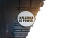 There is a circular sign under the roof of the building that says - Influence is Power