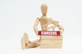 A wooden man sits near the wooden blocks, he holds in his hands a red block with the inscription - Careers