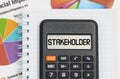 On the table are charts, a notebook and a calculator with the inscription - Stakeholder