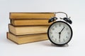 Books and an alarm clock lie on a white background Royalty Free Stock Photo