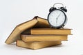 Books and an alarm clock lie on a white background Royalty Free Stock Photo