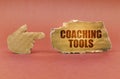 On a brown surface, a cardboard hand points to a sign that says - Coaching Tools Royalty Free Stock Photo