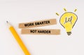 On a white surface, a luminous light bulb and pieces of paper with the inscription - Work Smarter Not Harder Royalty Free Stock Photo