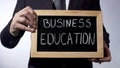 Business education written on blackboard, businessman holds sign, future Royalty Free Stock Photo