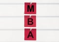 Business educatuion concept. red stickers on clips with text MBA acronym on white office table or wall with stripes, master of