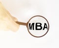 Business educatuion. magnifying glass with text MBA acronym in hand of man close up on light white background, master of business