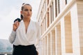 Business european elegant young woman fitting her cardigan clothes. Businesswoman goes to work in a business center