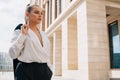 Business european elegant young woman fitting her cardigan clothes. Businesswoman goes to work in a business center Royalty Free Stock Photo