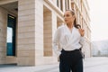 Business european elegant young woman fitting her cardigan clothes. Businesswoman goes to work in a business center Royalty Free Stock Photo