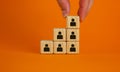 Business executive stacking wooden cubes with people icons on them in a pyramid shape in a conceptual image. Beautiful orange Royalty Free Stock Photo