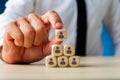 Business executive stacking wooden dices  with people icons on them in a pyramid shape Royalty Free Stock Photo