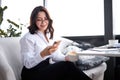 Business female sitting alone near big window in coffee shop during free time and working on smartphone Royalty Free Stock Photo