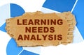 On the blue financial charts is a piece of cardboard that says - Learning Needs Analysis