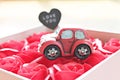 Miniature car model with love you on heart tag and red roses box on red background Royalty Free Stock Photo