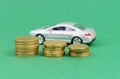 On a green background, coins with a toy car standing out of focus. Royalty Free Stock Photo