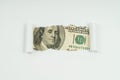 An image of a 100 dollar bill is visible in the torn hole of a sheet of paper Royalty Free Stock Photo