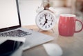 Closeup clock and red coffee cup on office desk