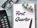 Phrase First Quarter written on note book with fake money,pen,calculator and eye glasses. Royalty Free Stock Photo