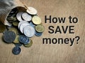 Phrase HOW TO SAVE MONEY written on wooden background with coins spill out from sack bag.