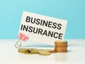 Phrase BUSINESS INSURANCE written on white card with coins.