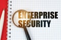 On the red surface is a pen, a notepad with the inscription - Enterprise Security and a magnifying glass