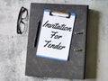 Selective focus paper clipboard written invitation for tender with pen,ring file and eye glasses.