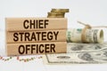 On the table are dollars, financial charts and wooden plates on which it is written - CHIEF STRATEGY OFFICER