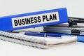 On the table are a notebook, a pen, documents and a folder with the inscription - BUSINESS PLAN Royalty Free Stock Photo