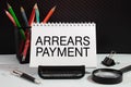Business and finance concept. On the table are a pen and a notebook with the inscriptions - Arrears Royalty Free Stock Photo