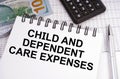 On the table there is money, a calculator and a notebook with the inscription - Child and Dependent Care Expenses