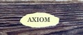 Business and finance concept. Top view of piece of paper written word AXIOM on wooden background