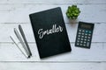 Business and finance concept.Top view of plant,calculator,pen and notebook written with Smaller. Royalty Free Stock Photo