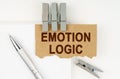 On a white background lies a notebook, a pen, clothespins and cardboard with the inscription - Emotion Logic Royalty Free Stock Photo