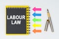 On a white background lies a pen, arrows and a notebook with the inscription - LABOUR LAW