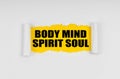 A window is made in the paper, where on a yellow background the inscription - Body Mind Spirit Soul