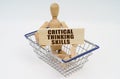 A wooden man sits in a shopping basket, holding a sign in his hands - Critical Thinking Skills Royalty Free Stock Photo