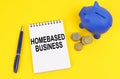 On a yellow surface, a piggy bank, coins and a notepad with the inscription - Homebased business Royalty Free Stock Photo