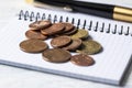 Business, finance or investment concept. Coins, checkbook or notebook and fountain pen. White wooden background Royalty Free Stock Photo