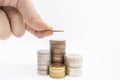 Business Finance, Money Saving Concept. Close up of man hand holding a coin and put it on top of stack of coins on white backgound Royalty Free Stock Photo