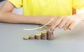 Business, finance, and saving concept - Hand hold and stacking coins on gray table with white growth up arrow. A girl collects