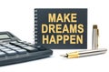 On a white background, there is a calculator, a pen and a black notebook with the inscription - MAKE DREAMS HAPPEN