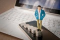 Business man standing on top of stack of silver coins and smartphone with laptop in the background. Royalty Free Stock Photo