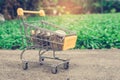 Various money coins Baht in yellow mini shopping cart or supermarket trolley set on concrete floor. Royalty Free Stock Photo