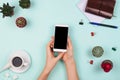 Business flatlay arrangement with woman`s hands holding smartphone with black copyspace and other stationary and office accessori