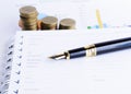 Business Fountain pen and Coins stack on document report