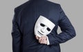 Businessman hide the mask in hand behind his back. Royalty Free Stock Photo