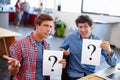 Business is full of questions. Portrait of two coworkers looking confused while holding question mark signs. Royalty Free Stock Photo
