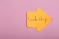 Business future and motivation concept - orange sticker in the shape of an arrow and text "Next step" on pink background Royalty Free Stock Photo